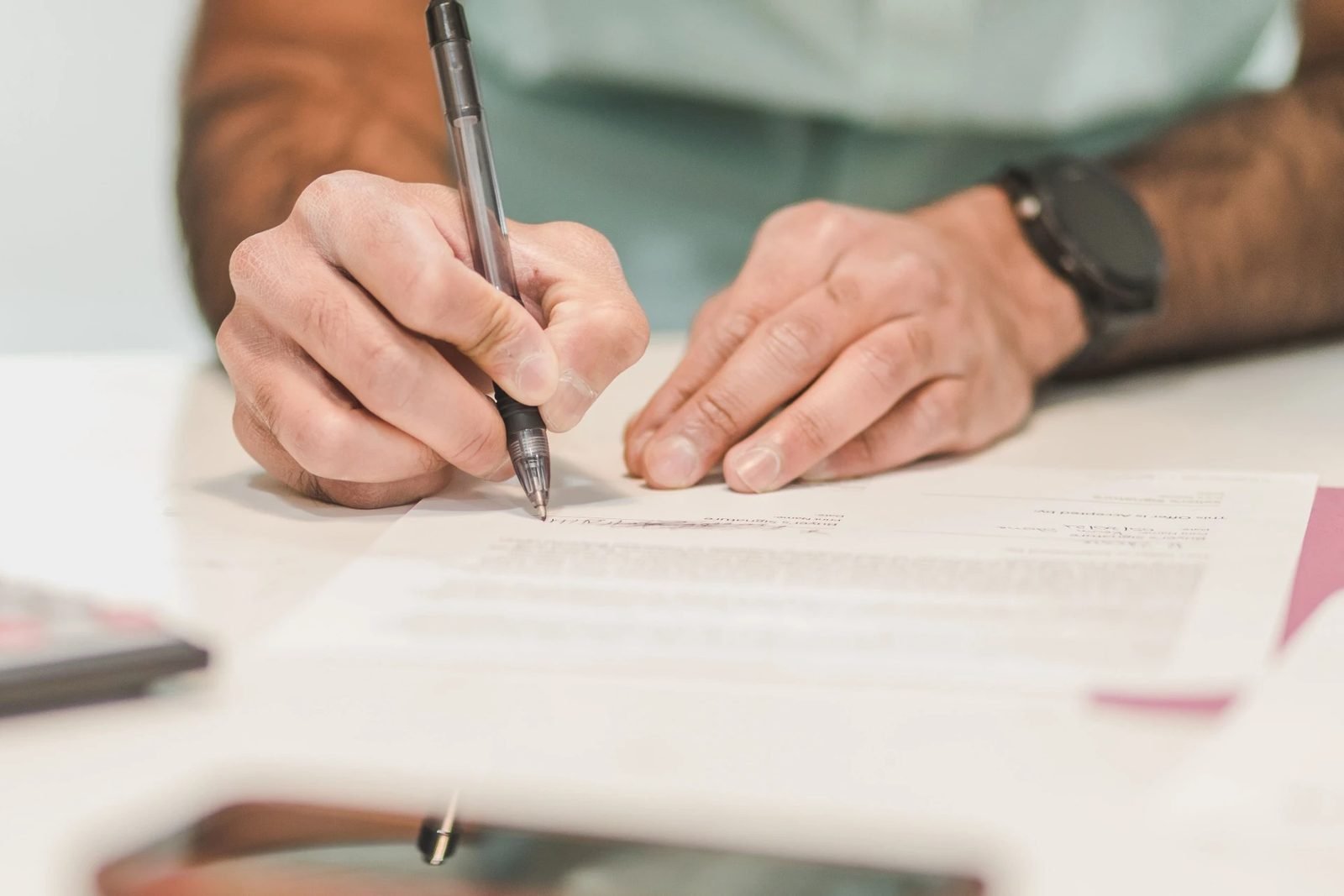 Person reviewing paperwork at a table before making a decision.